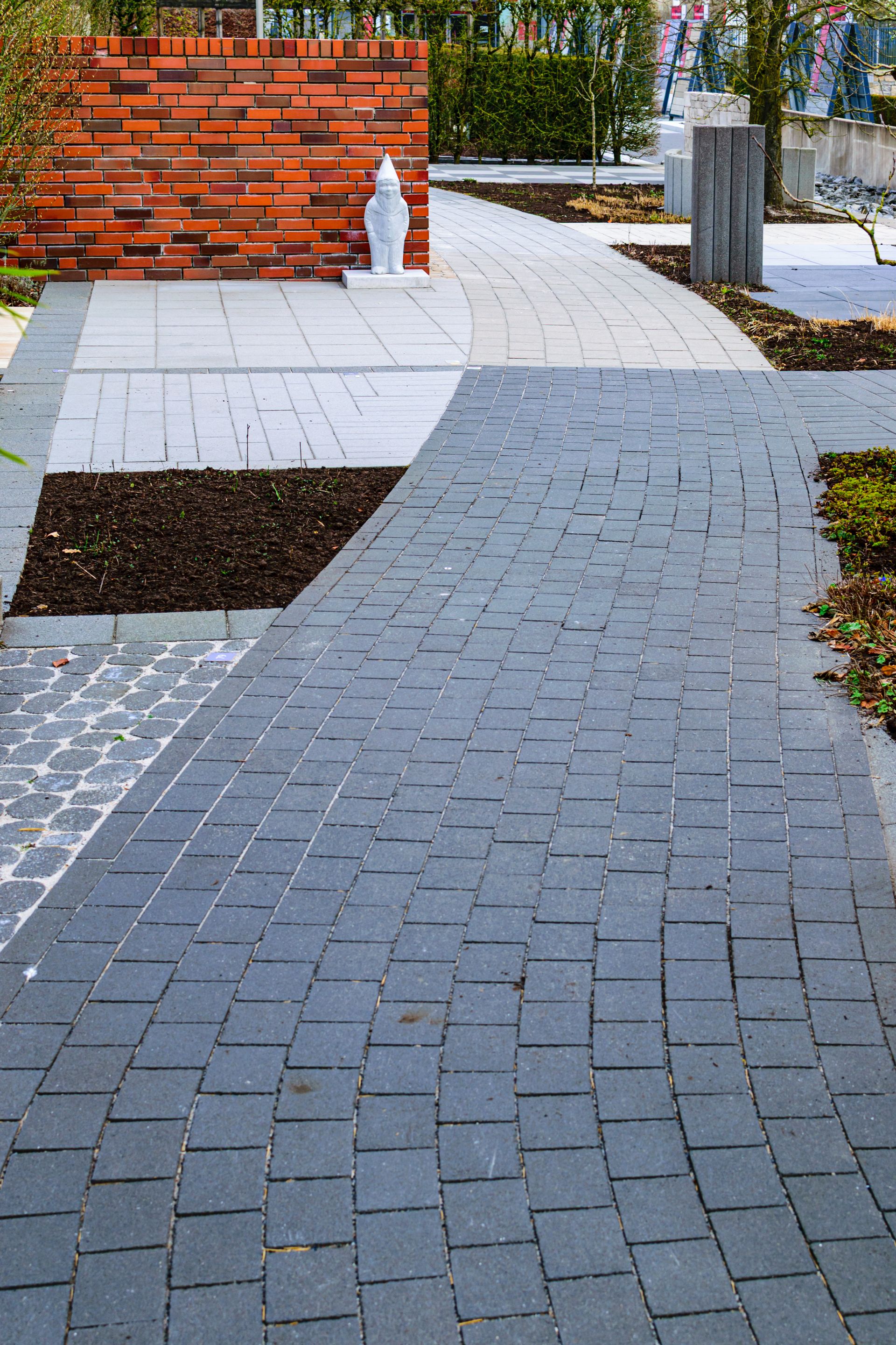 Gebogen wandelpad in rode klinkers door een moderne tuin
